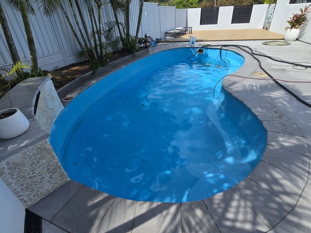 Completed fibreglass pool resurfacing Gold Coast kidney shaped pool with pristine blue finish modern backyard
