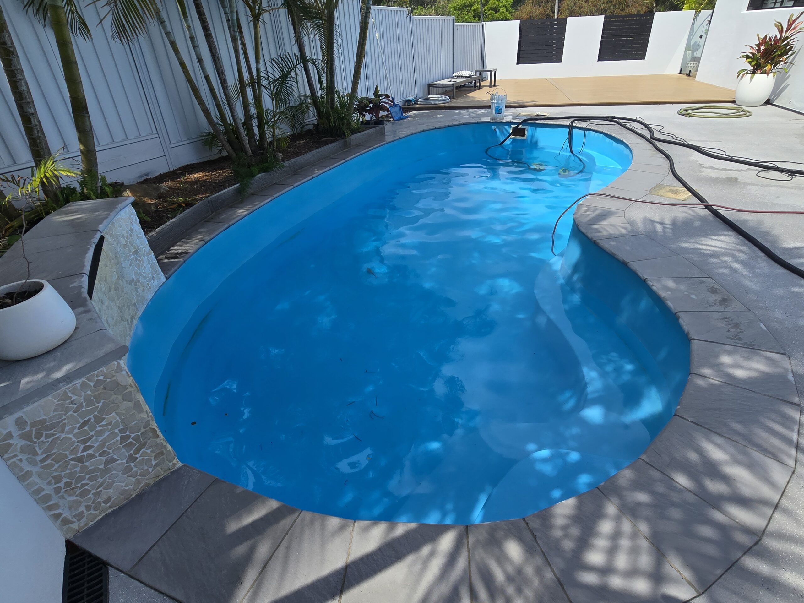 Completed fibreglass pool resurfacing Gold Coast kidney shaped pool with pristine blue finish modern backyard