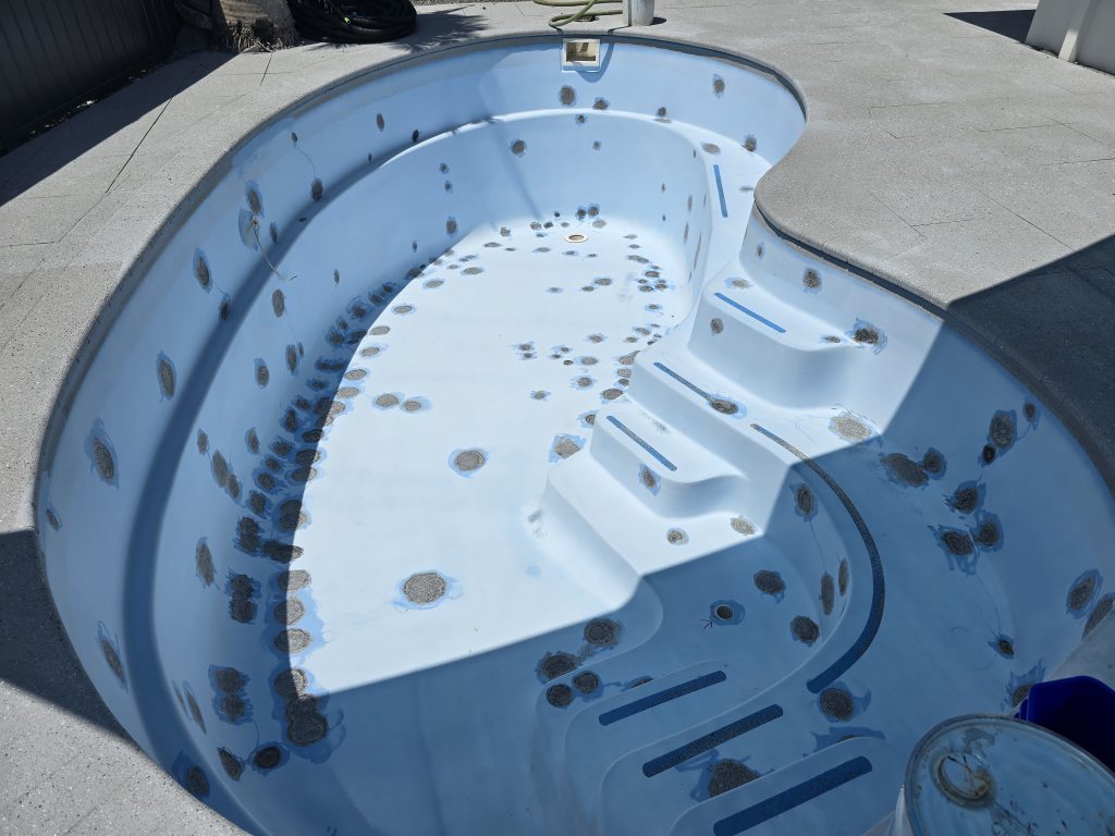 Severe osmosis blisters on fibreglass pool Gold Coast showing extensive damage requiring resurfacing repair work