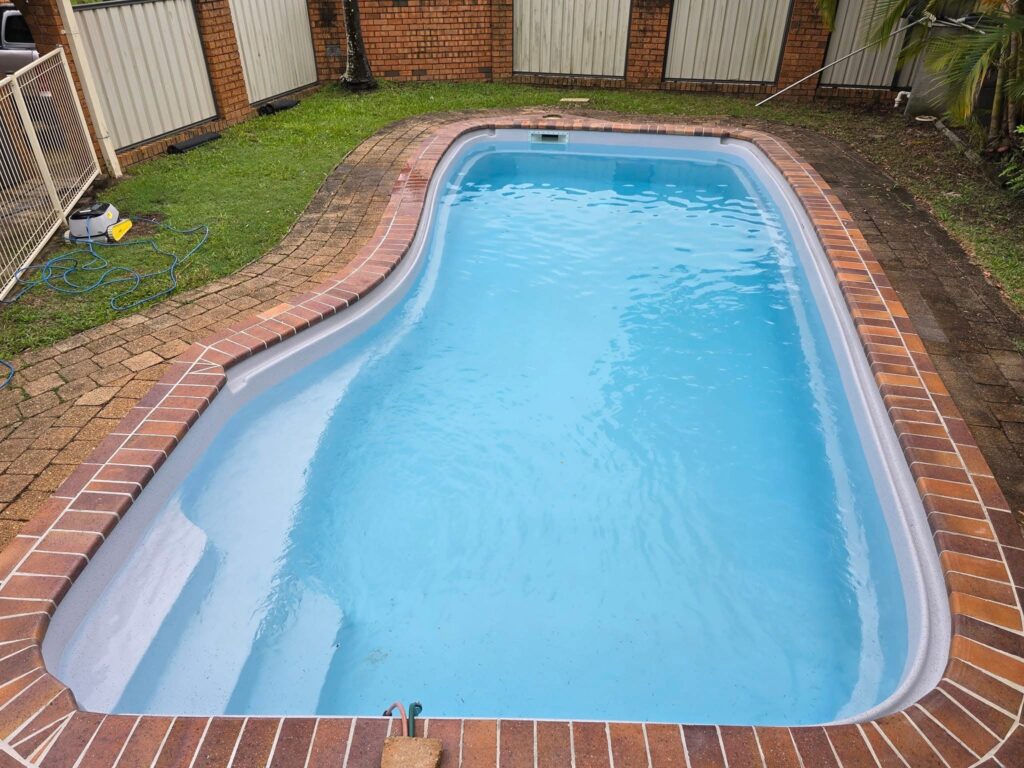 Fibreglass pool resurfacing Gold Coast completed renovation with pristine blue finish and brick coping residential