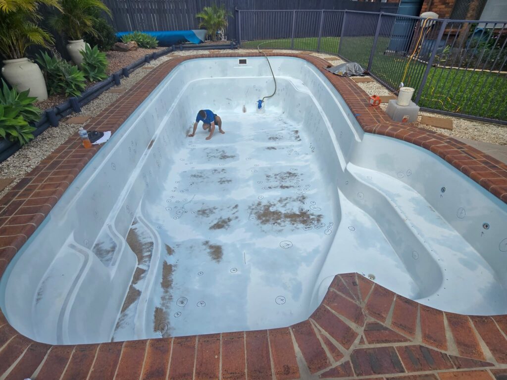 Fibreglass pool with rust stains and discolouration Gold Coast during cleaning before resurfacing repair work