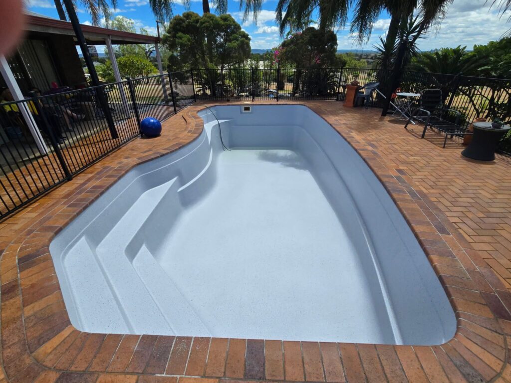 Pool repairs and resurfacing Gold Coast completed fibreglass work showing smooth light grey finish pool